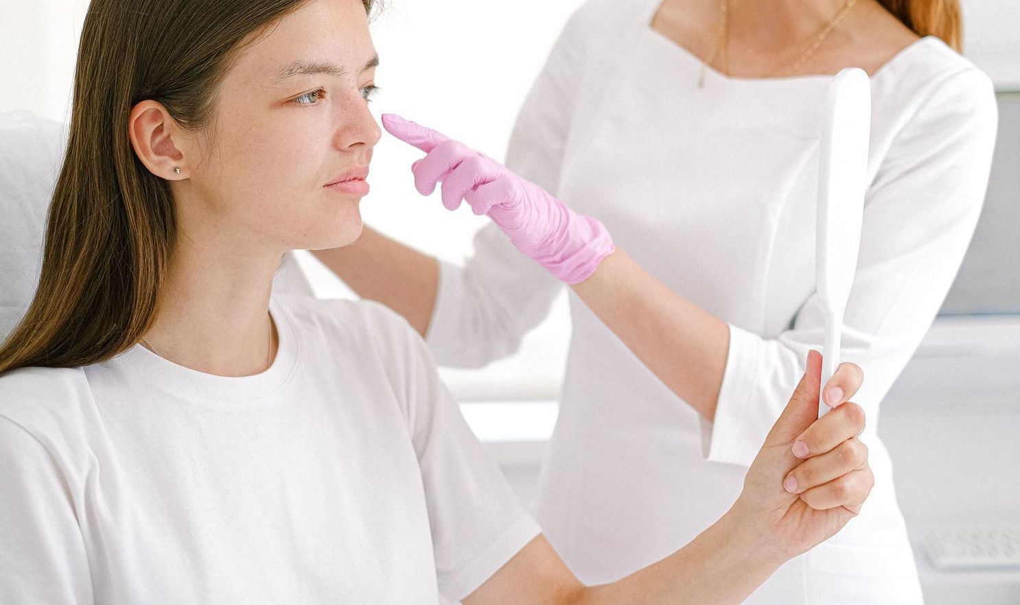 Woman receiving a facial consultation from a cosmetologist in a clinic.